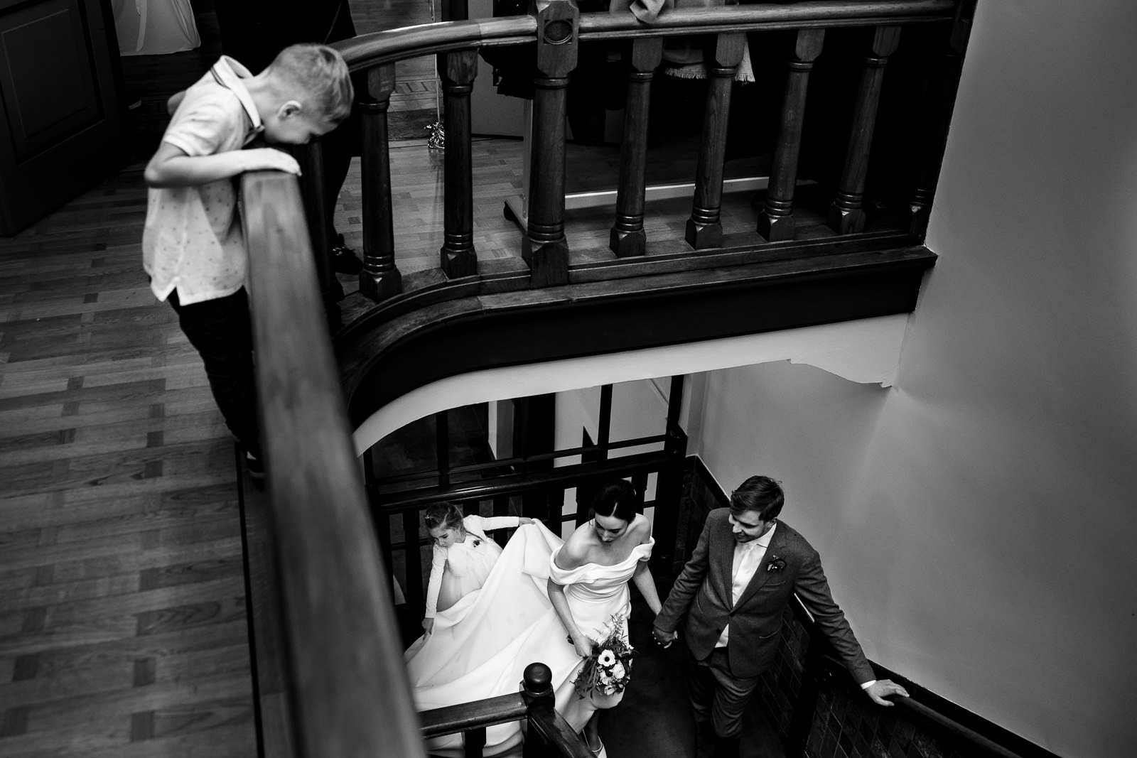 Bruidspaar komt aan bij het Nutshuis en wordt opgewacht door de neefje boven aan de trap vastgelegd door Trouwfotograaf Den Haag Paco van Leeuwen