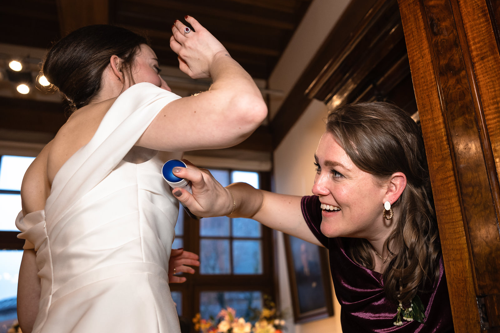 Bruid krijgt wat extra deodorant opgespoten door beste vriendin vastgelegd door Trouwfotograaf Den Haag Paco van Leeuwen