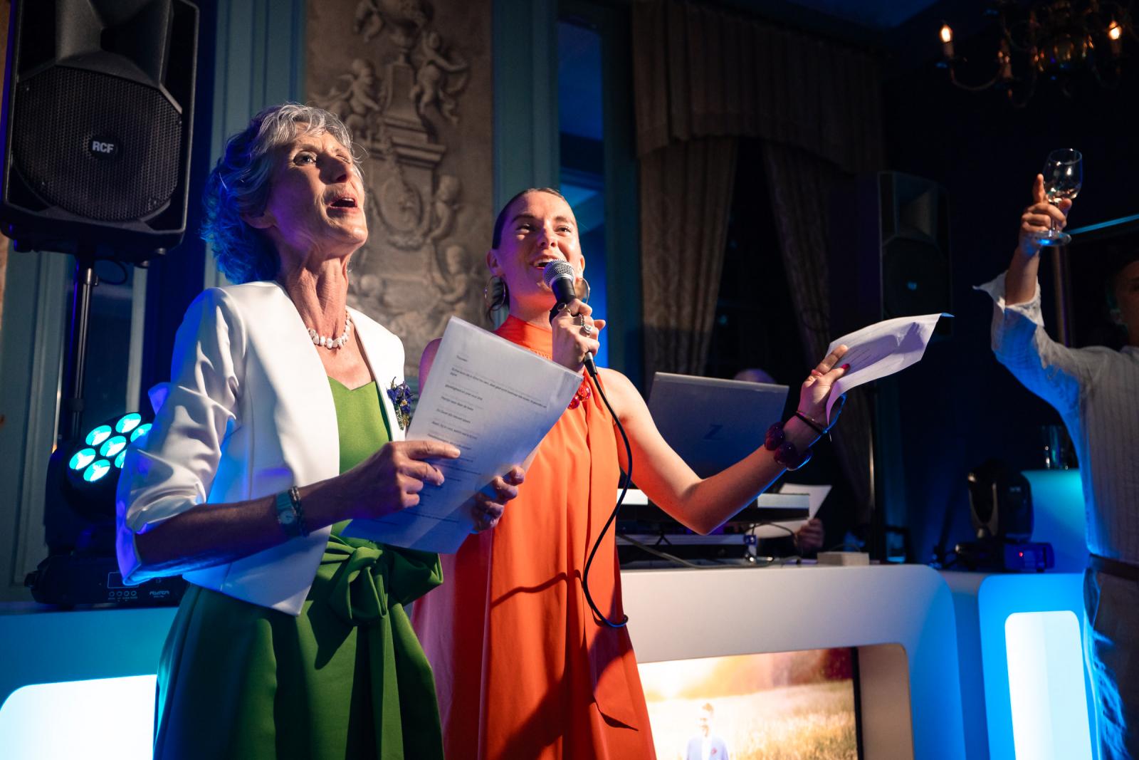 Moeder en zus zingen enthousiast met een microfoon en songtekst in de hand voor de DJ-booth