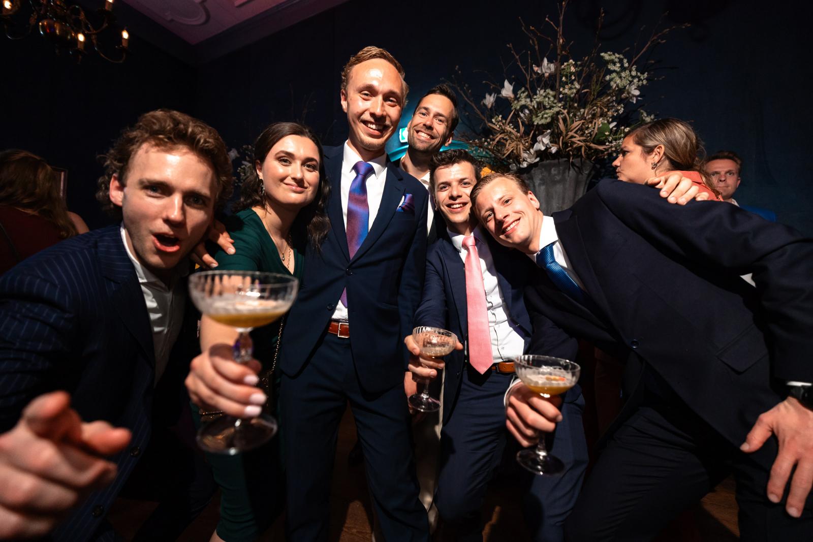Een groep vrienden poseert vrolijk met cocktailglazen in hun hand, dicht op de camera gefotografeerd