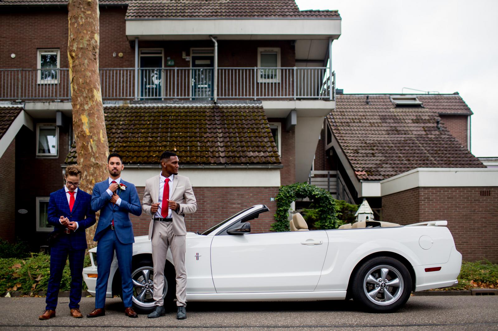 Bruidegom en getuigen bij Ford Mustang