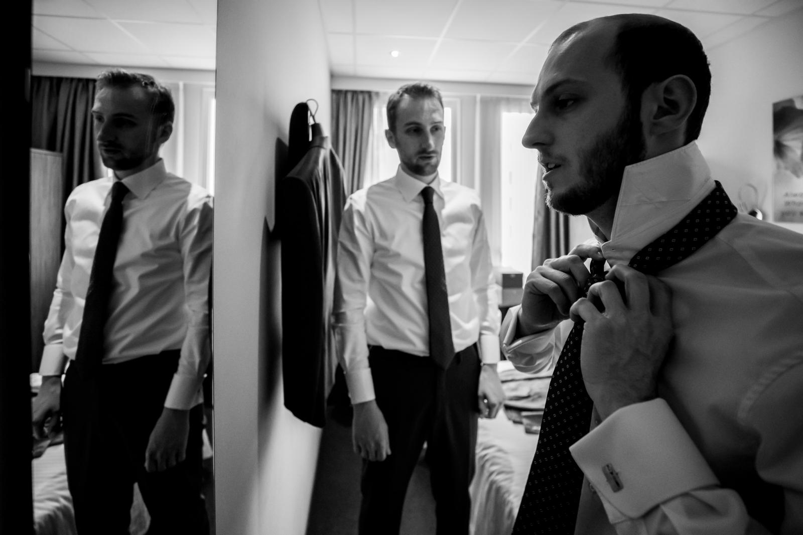 Bruidegom doet stropdas aan voor spiegel