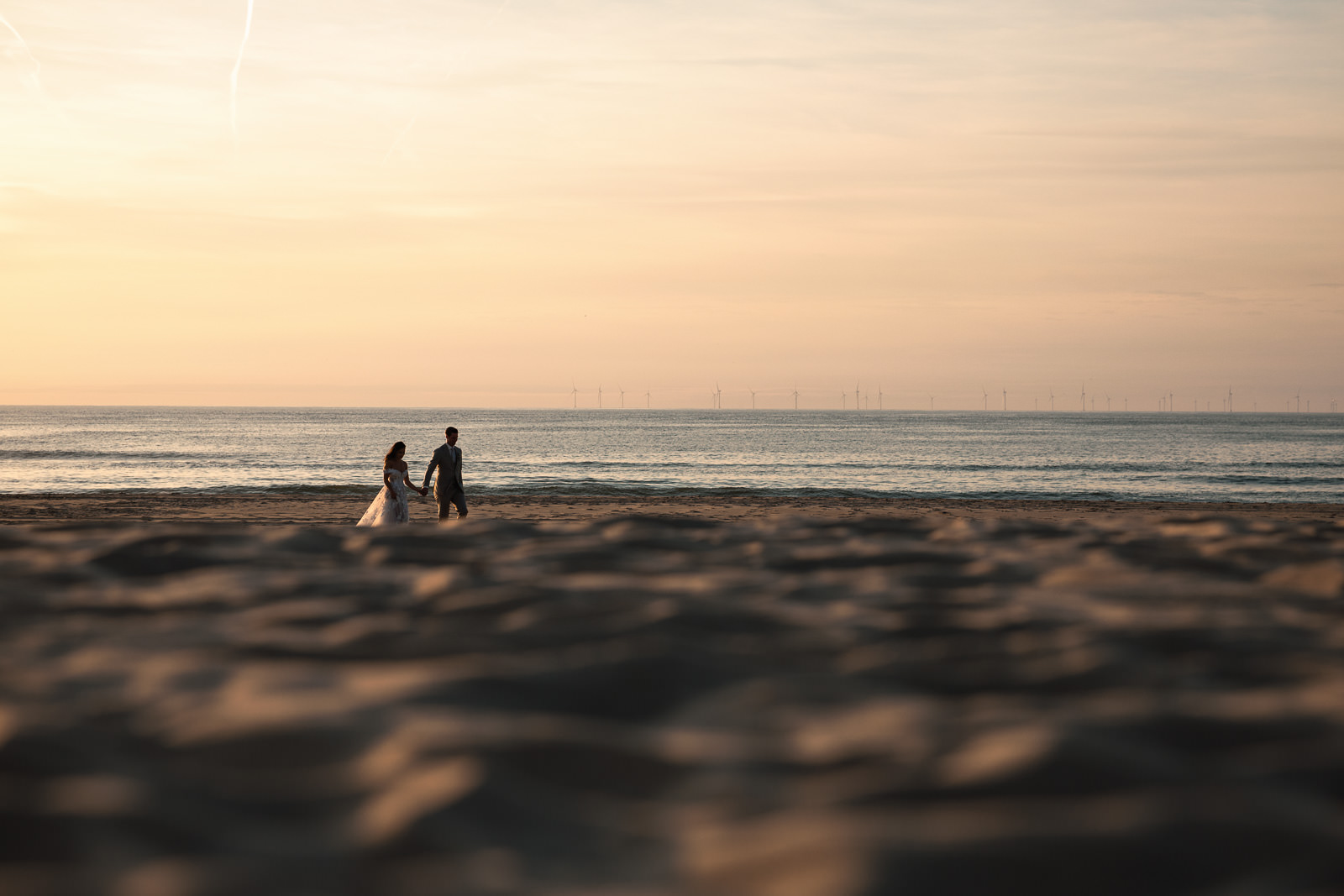 bride and groom walking on the beach together during sunset