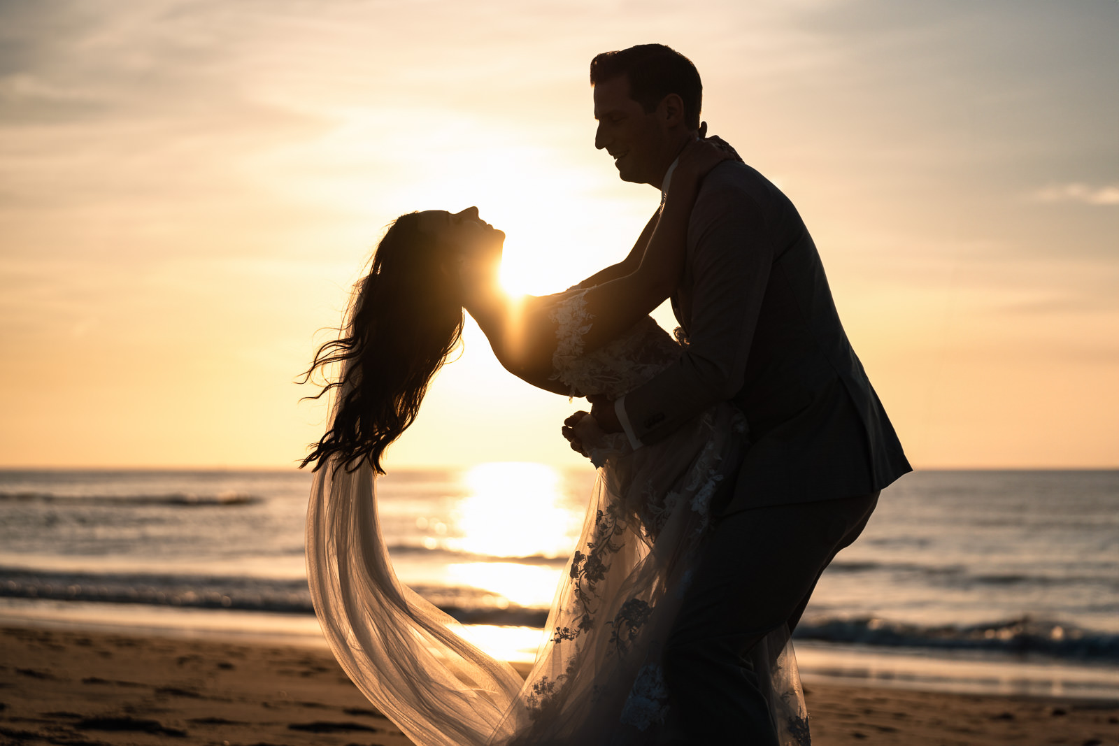 Bride and groom fun silhouette during beach wedding sunset