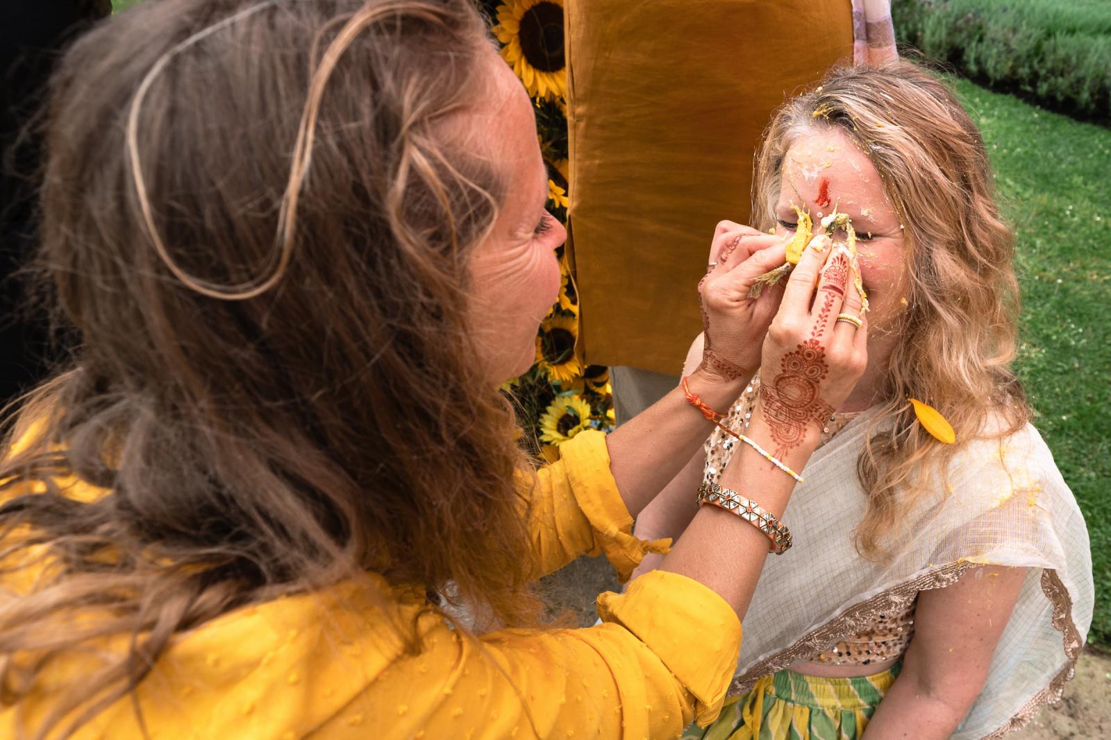 Bruid wordt ingesmeerd met yoghurt tijdens Indiase Haldi ceremonie op terras van Landgoed Duin en Kruidberg