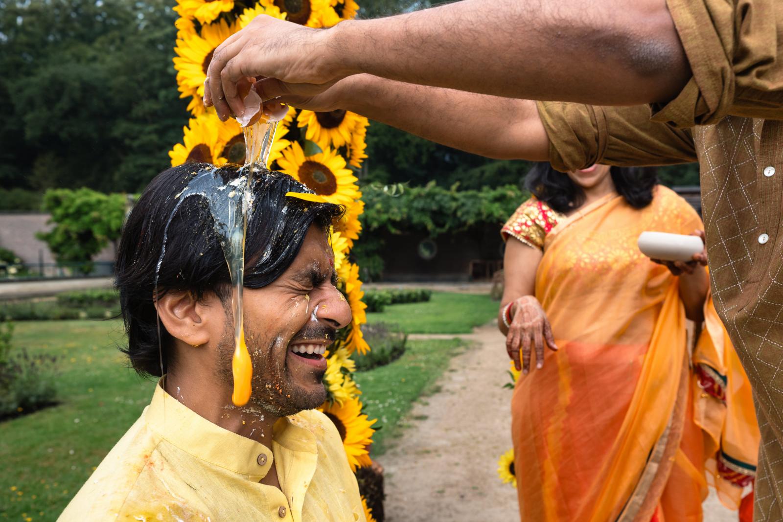 Bruid krijgt een ei over zijn hoofd tijdens Indiase Haldi ceremonie op terras van Landgoed Duin en Kruidberg