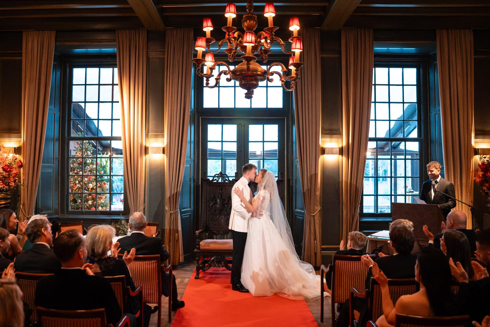 Eerste kus van het bruidspaar bij het altaar, omringd door kerstdecoratie.
