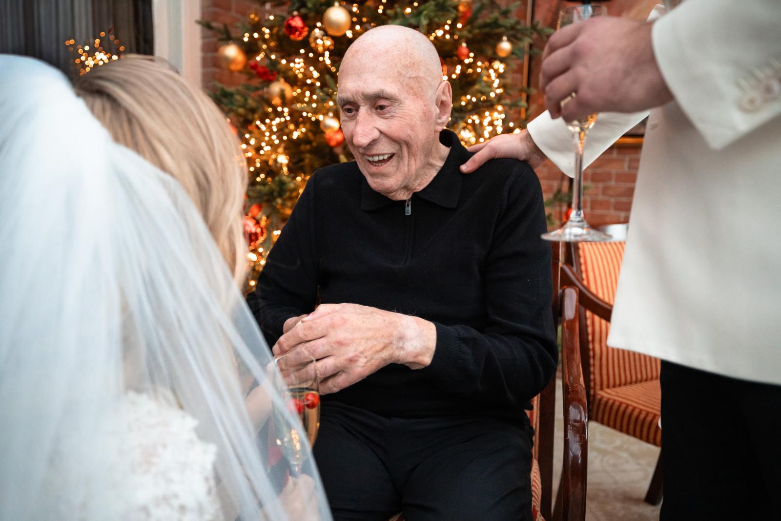 Bruid feliciteert een opa bij de kerstboom, warme familieband.