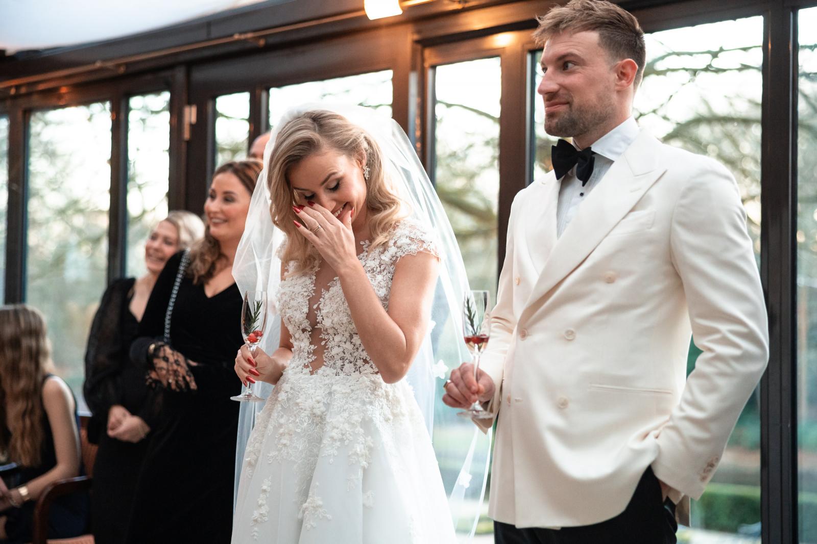 Bruid lacht en pinkt een traan weg tijdens de kerstbruiloft receptie.