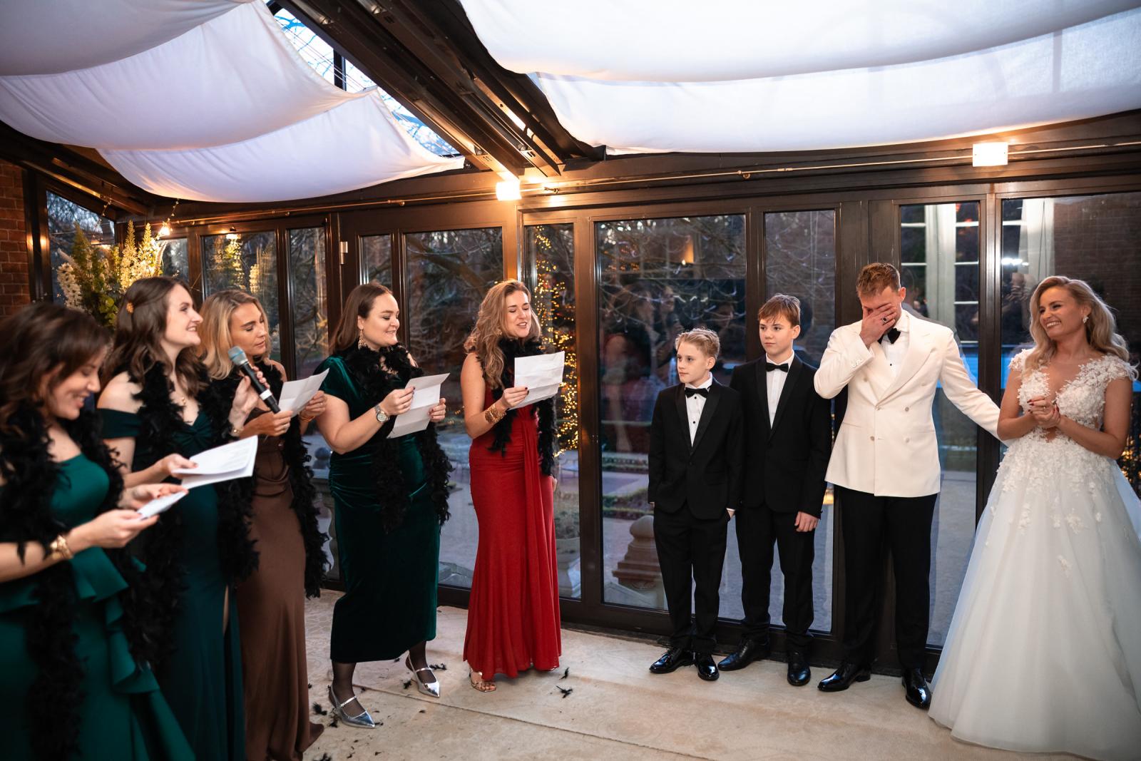 Vriendinnen zingen een verrassingslied voor het bruidspaar, bruidegom ge�motioneerd.