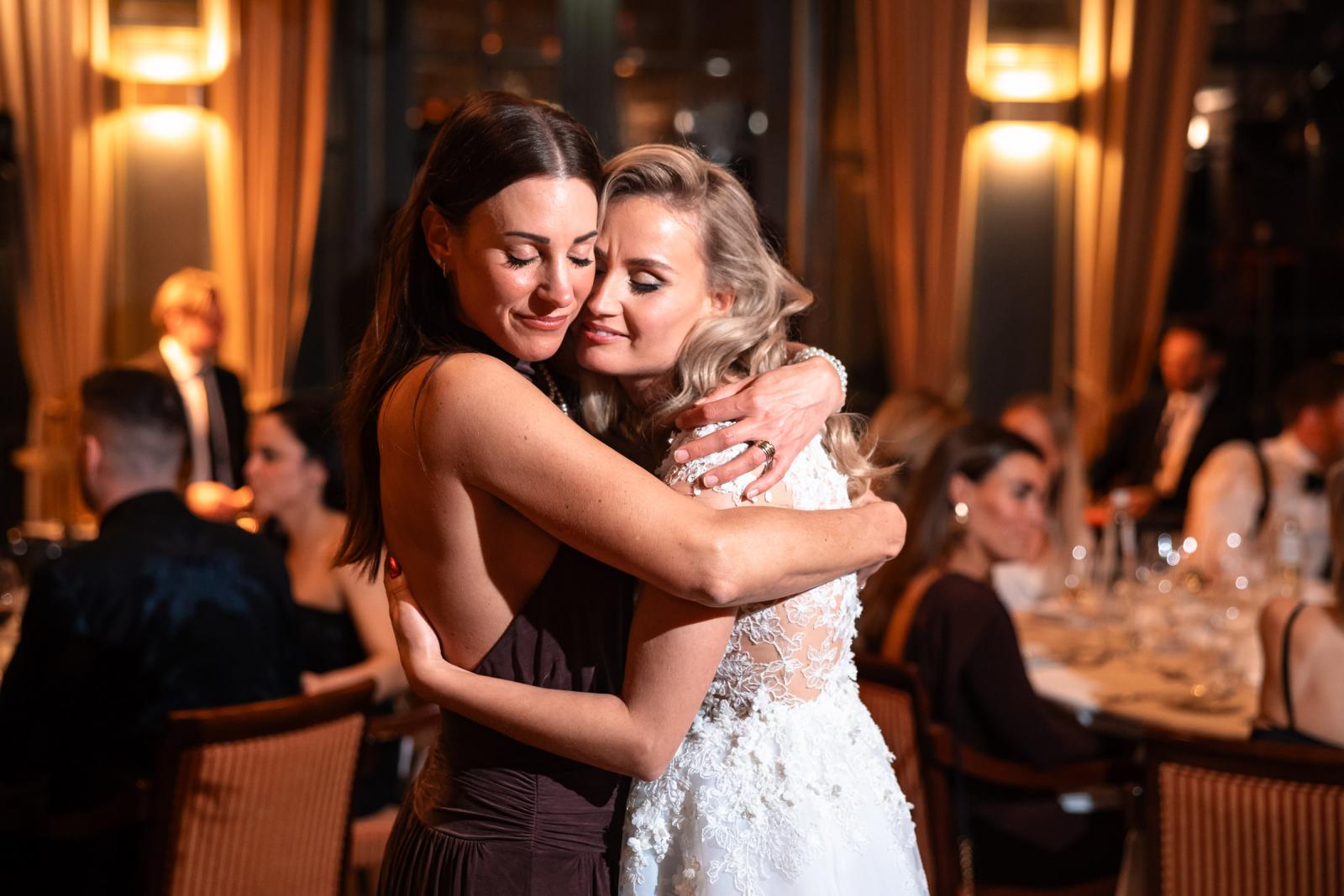 Carlijn en haar zus omhelzen elkaar tijdens het diner, warme kerstbruiloft sfeer.