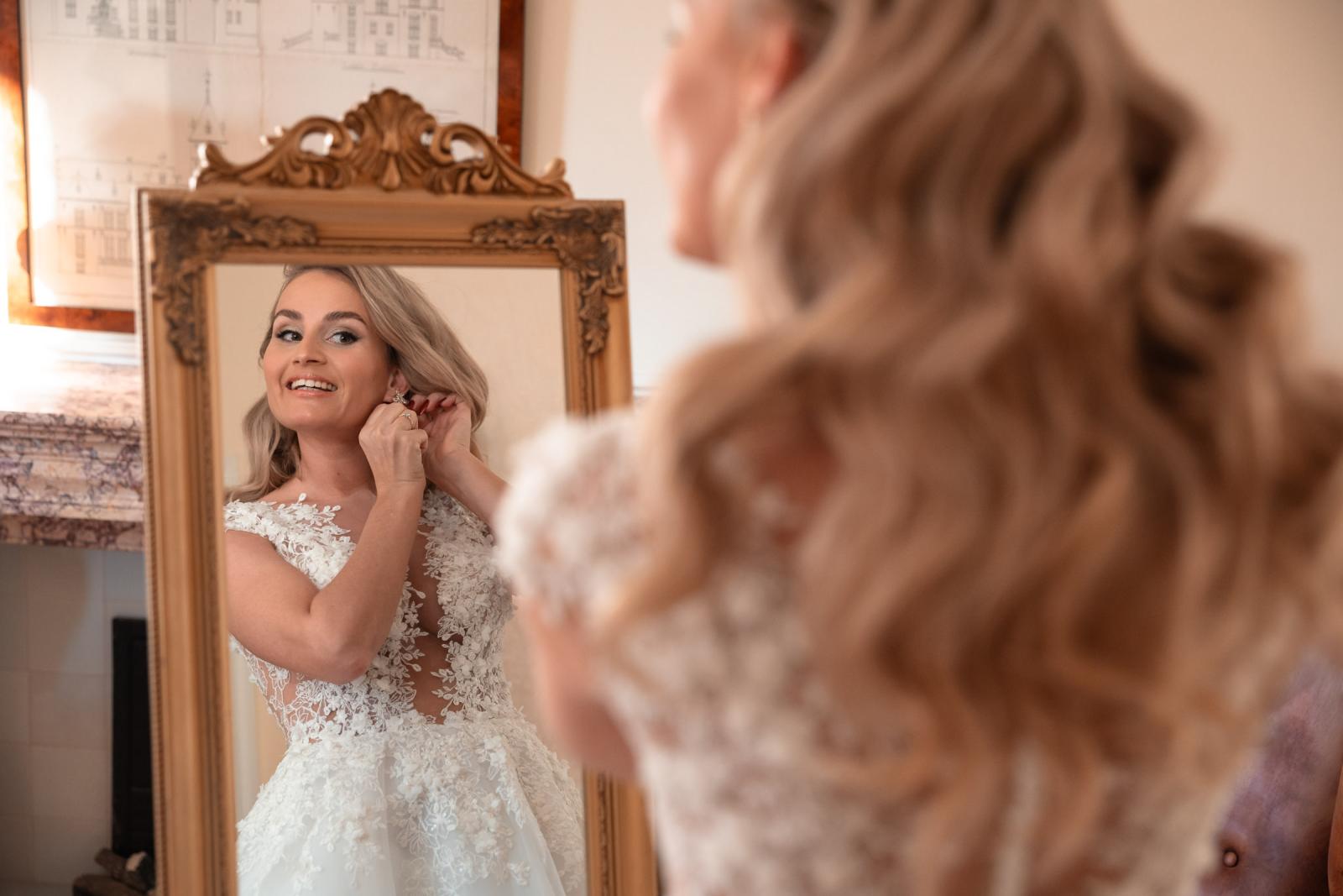 Bruid doet oorbellen in voor de spiegel tijdens kerstbruiloft Kasteel de Wittenburg.