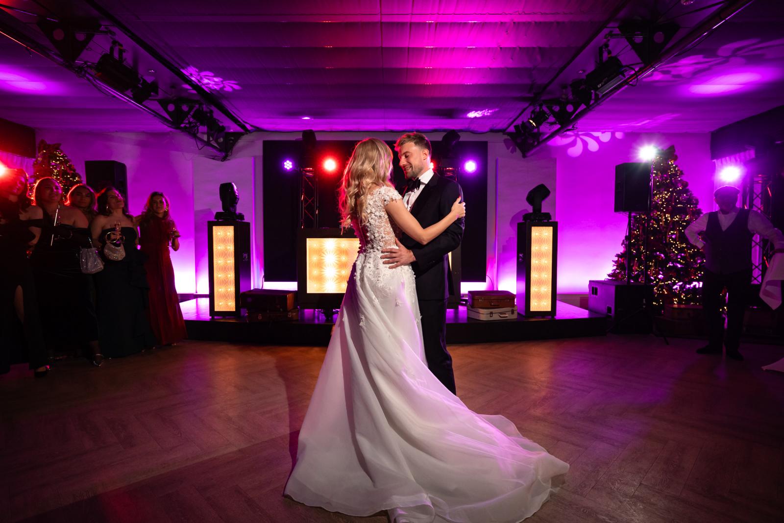 Bruid en bruidegom openen samen de dansvloer, kerstbomen en art deco lichten.