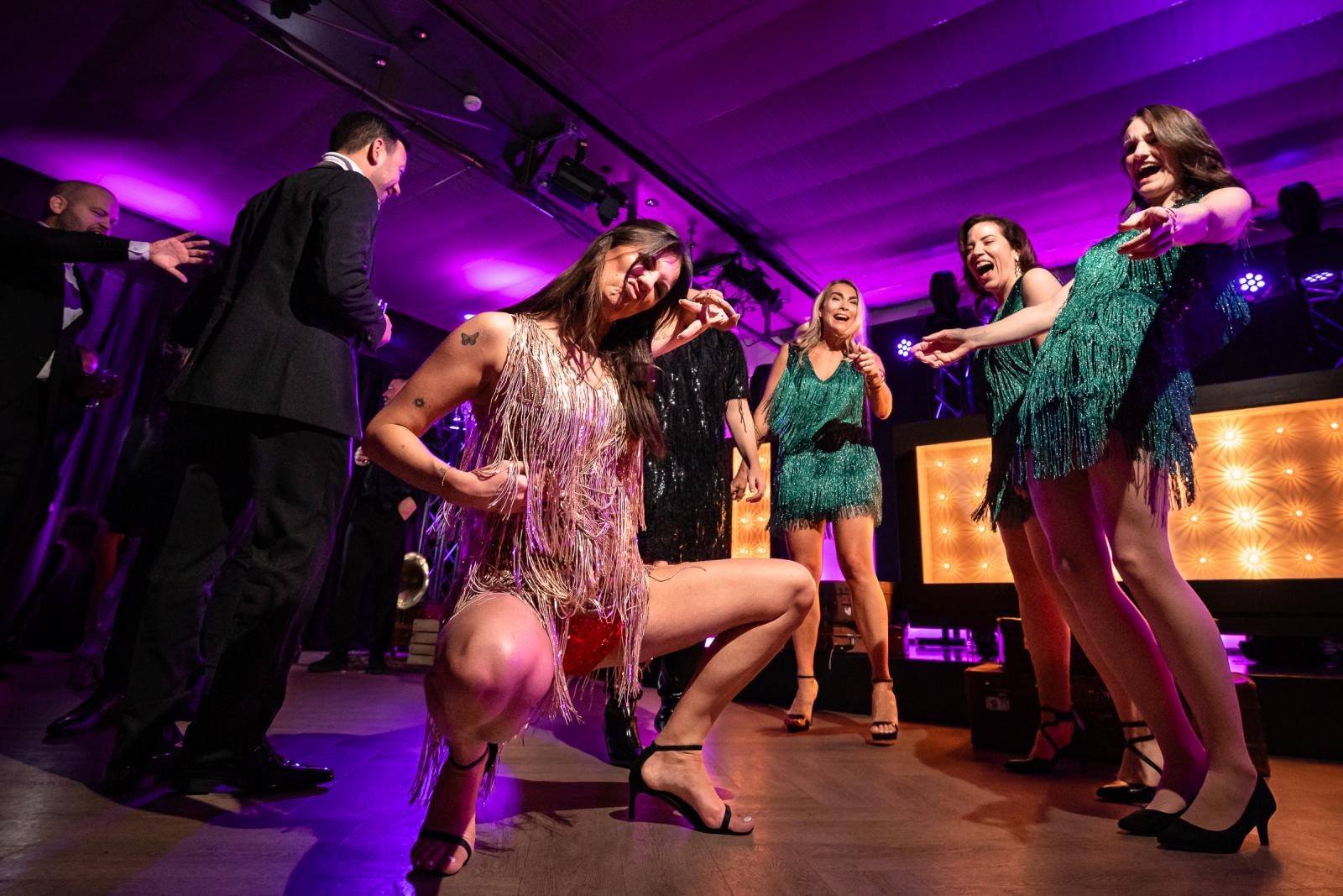 Vriendinnen in flapperjurken dansen op de dansvloer, feestelijke kerstsfeer.