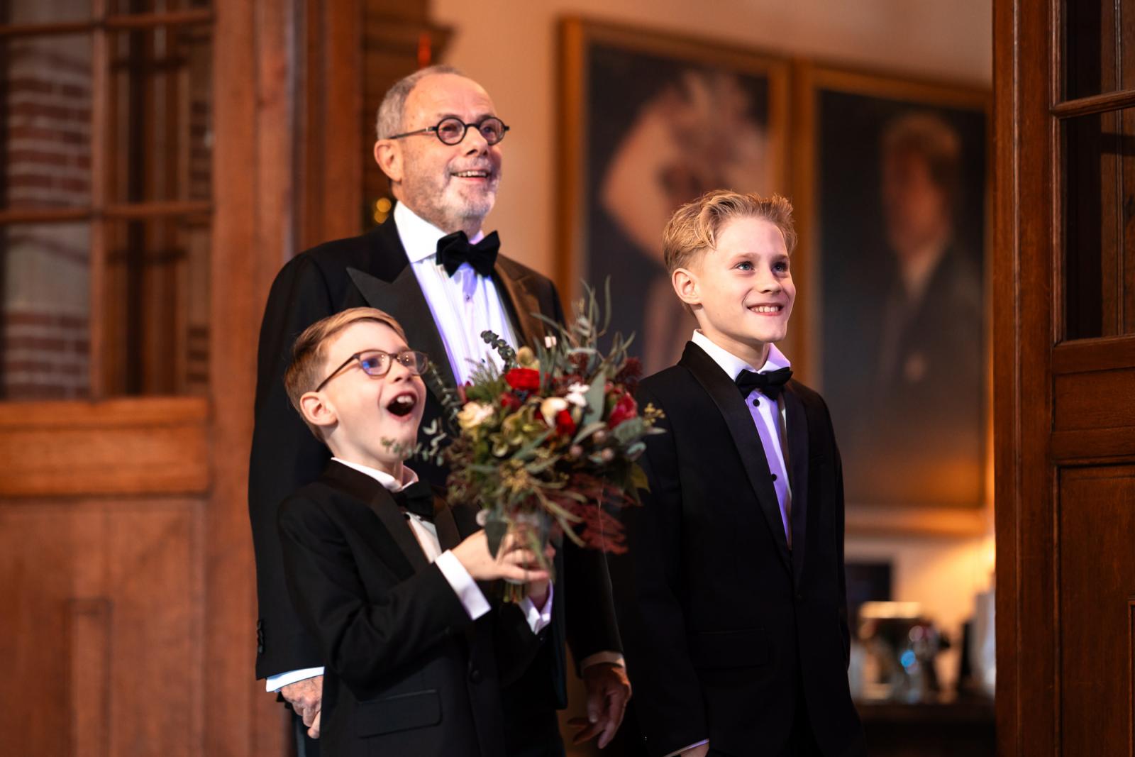 Vader van de bruid en haar zoons in smoking, vol verwachting bij de kersttrap.