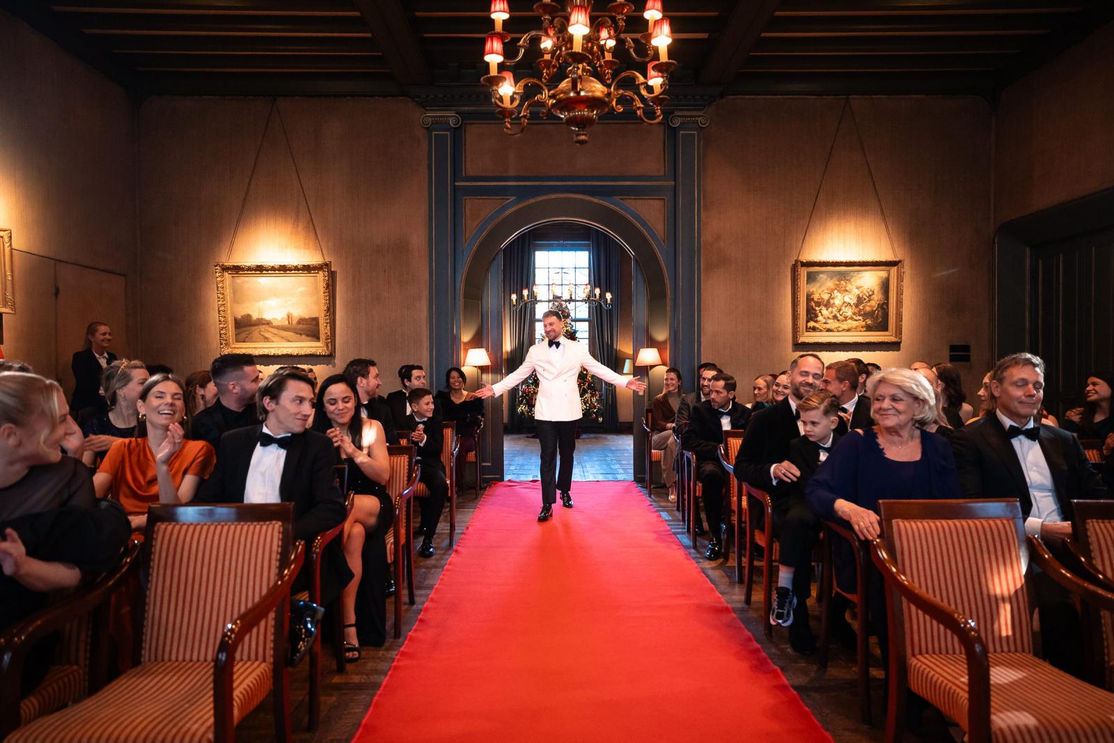 Bruidegom maakt entree over de rode loper in de ceremonie zaal, kerstbruiloft.
