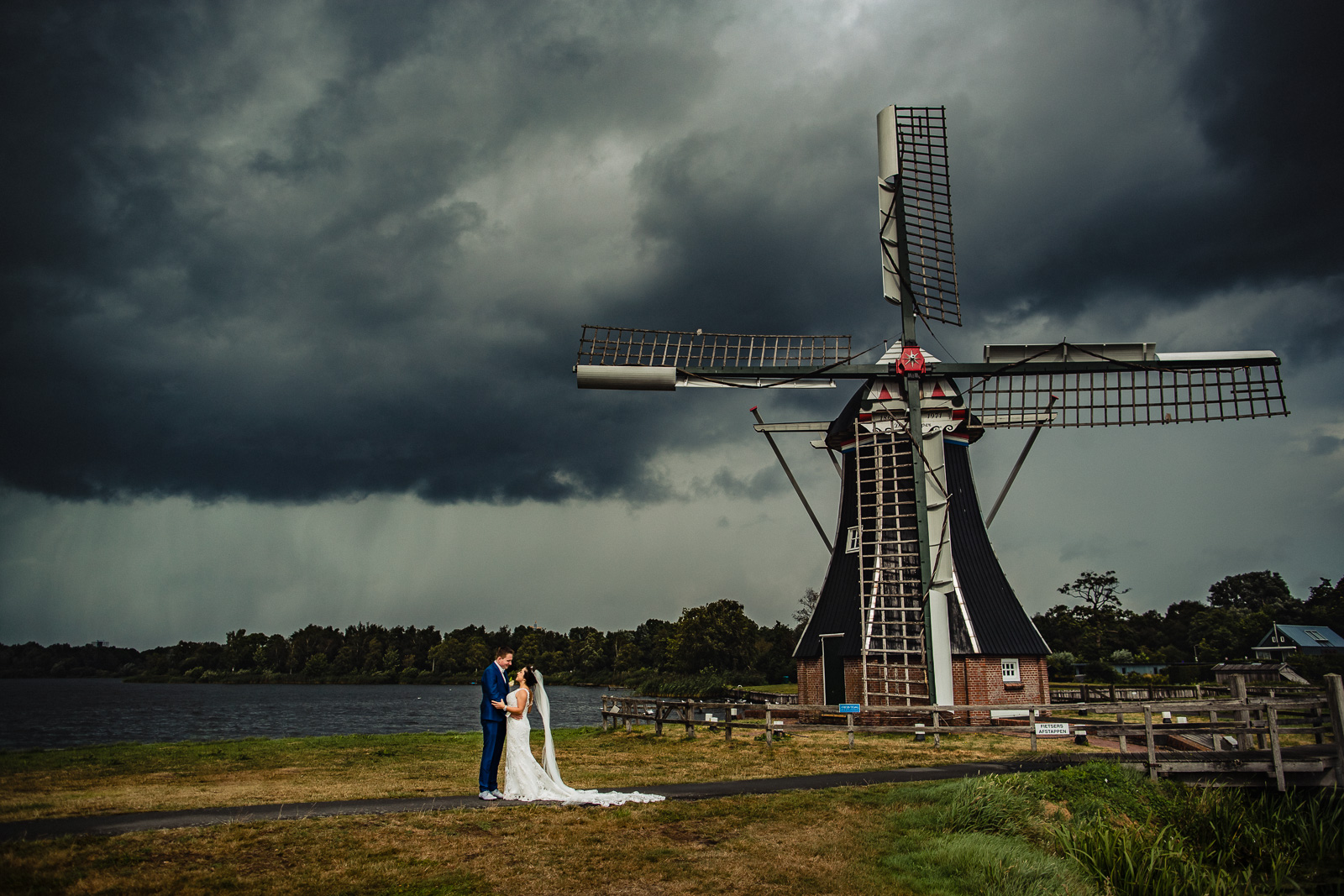Dreigende wolken boven het bruidspaar voor een molen in Groningen