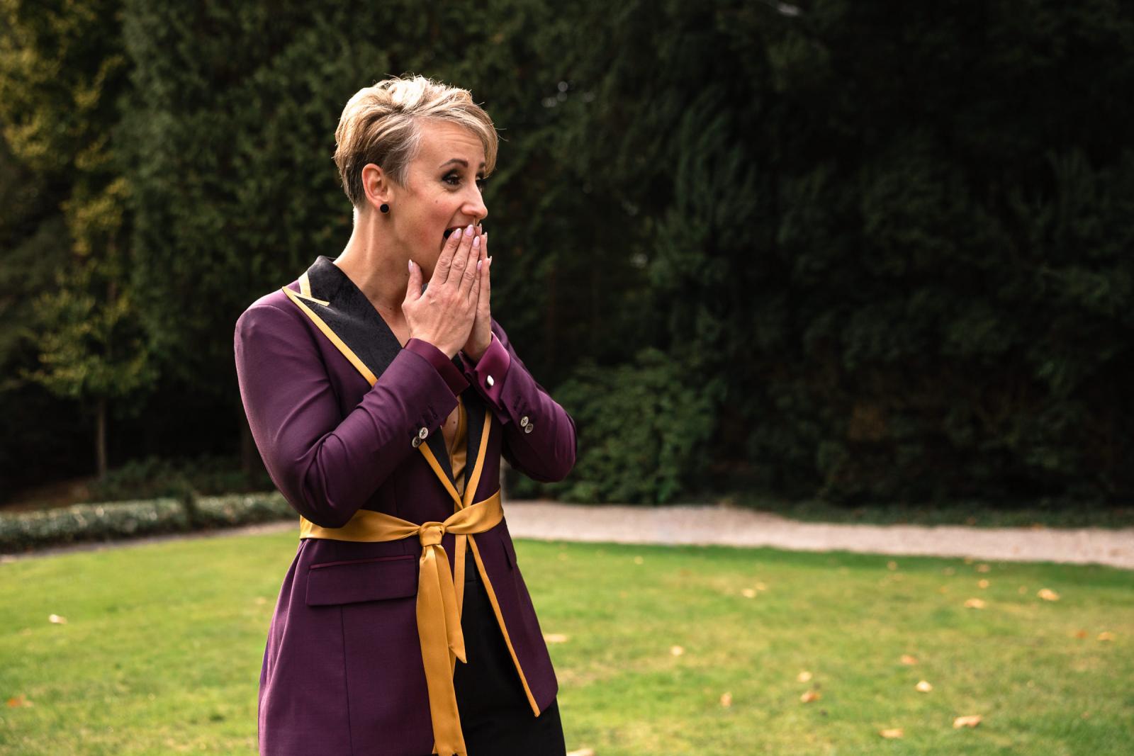 De andere bruid reageert ontroerd bij het zien van haar partner tijdens de first look in de tuin van het kasteel.