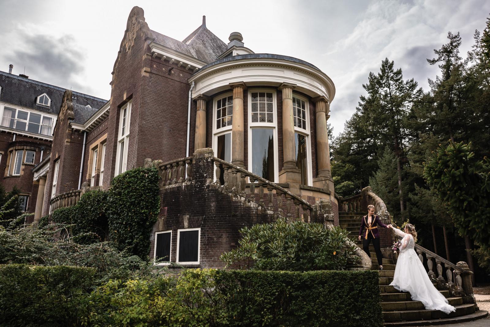 De bruiden lopen hand in hand de trap af bij Kasteel De Hooge Vuursche, een romantisch en statig decor.