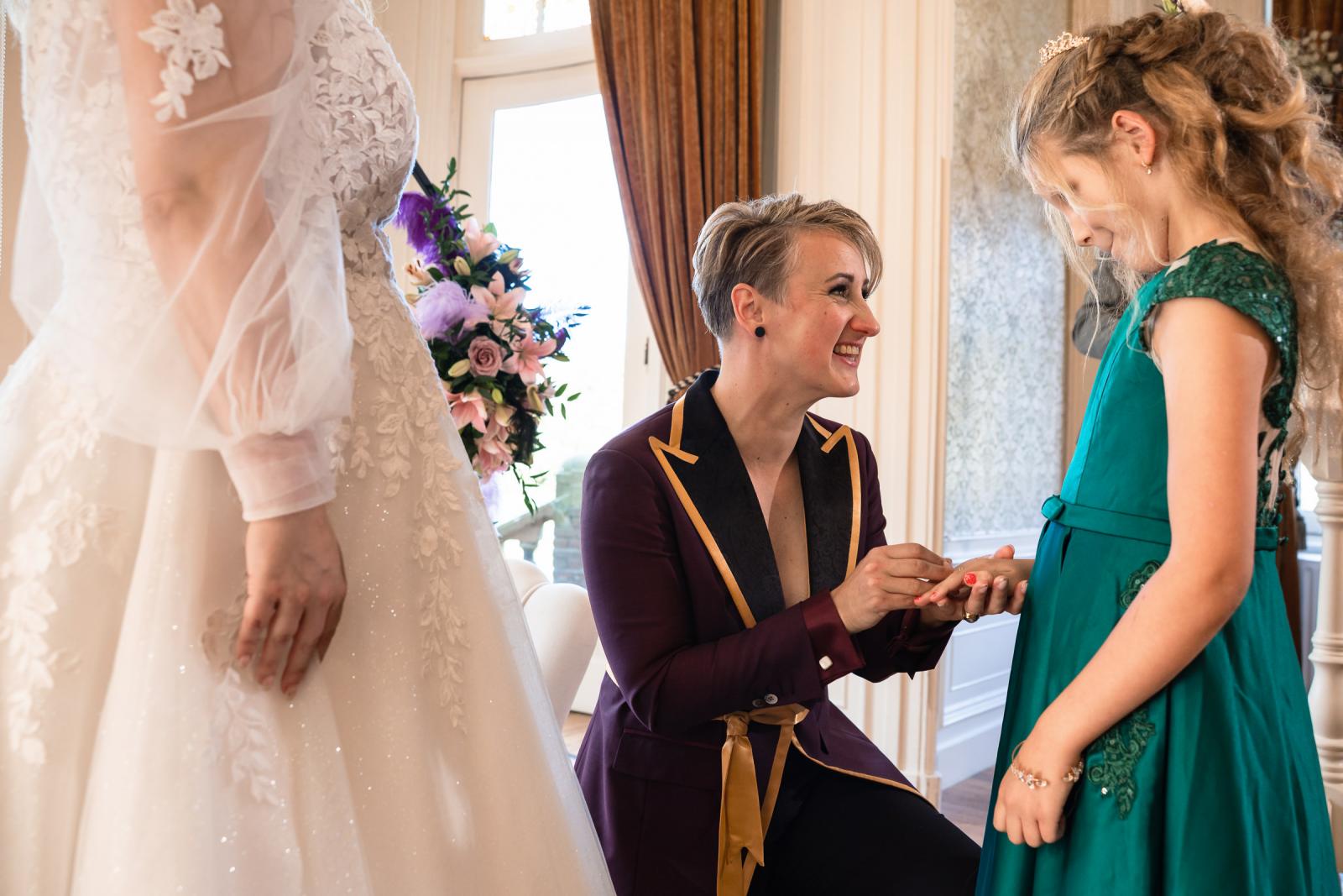 Een van de bruiden schuift liefdevol een ring om de vinger van hun dochter tijdens de ceremonie.