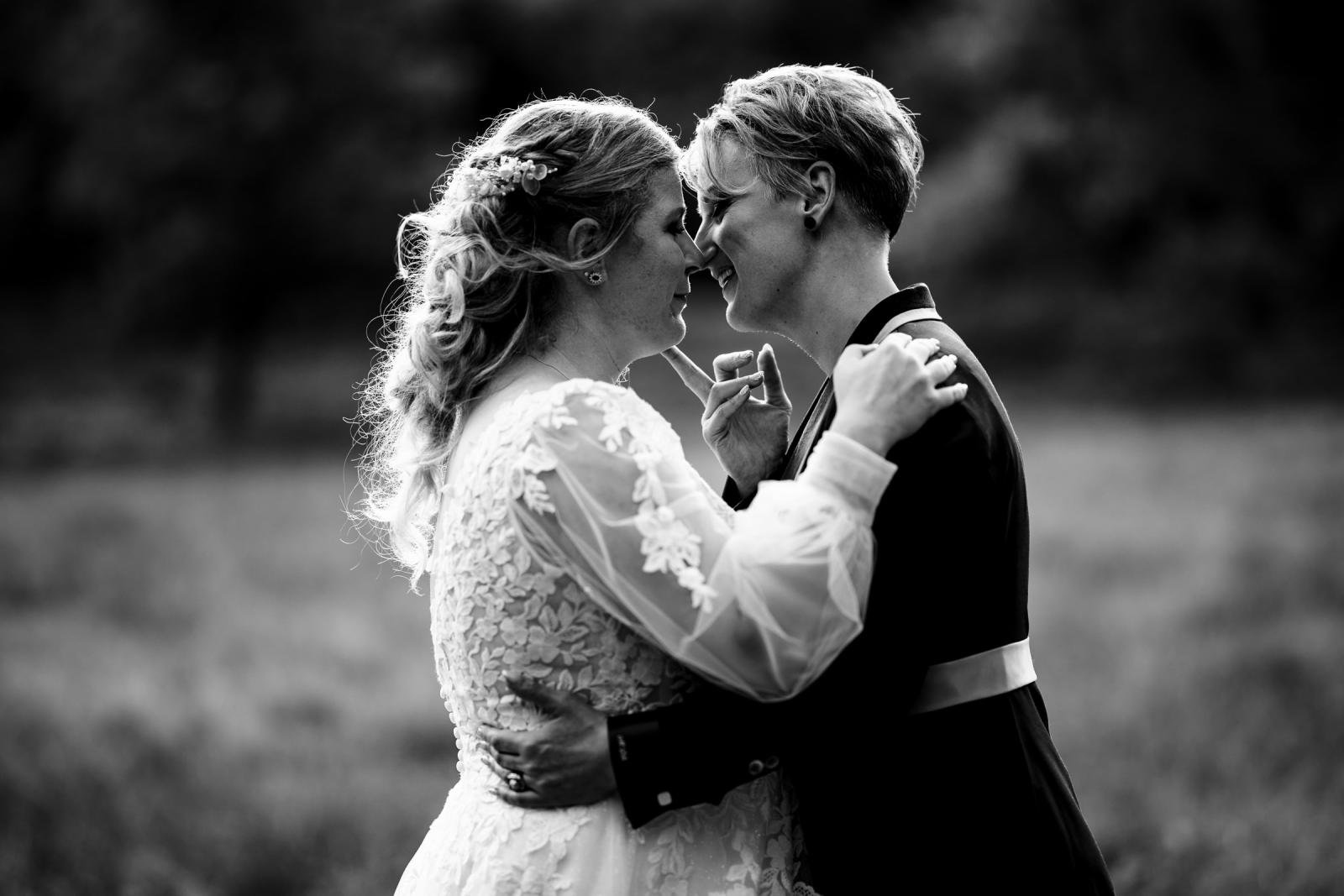 Zwart-wit portret van de bruiden in een intiem moment, met hun voorhoofden tegen elkaar.