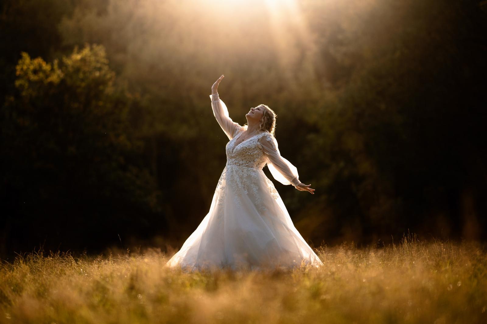 De bruid in witte jurk danst stralend in het gouden zonlicht van de late middag.