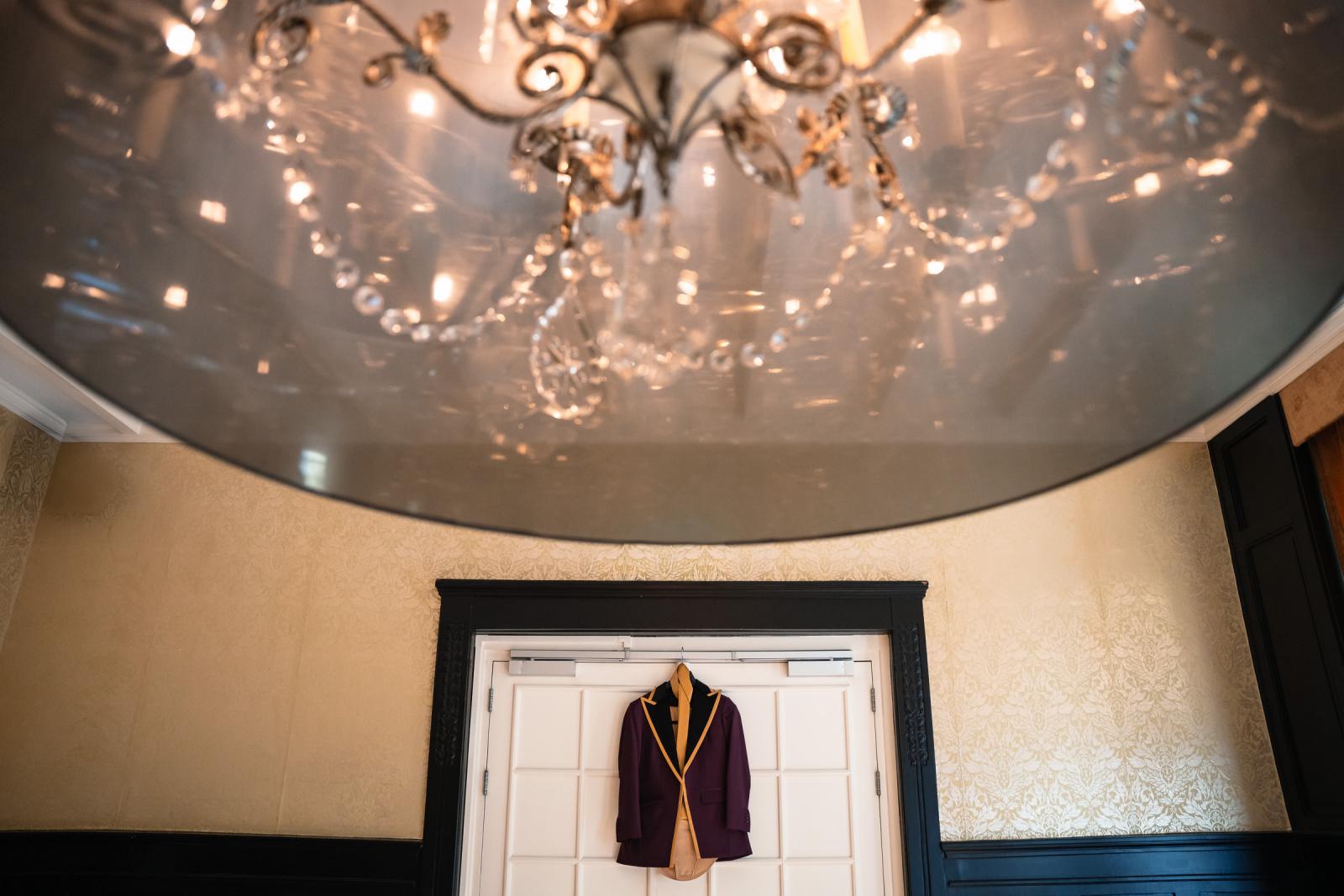 Het paarse trouwjasje van de tweede bruid hangt klaar onder een kroonluchter in het kasteel.
