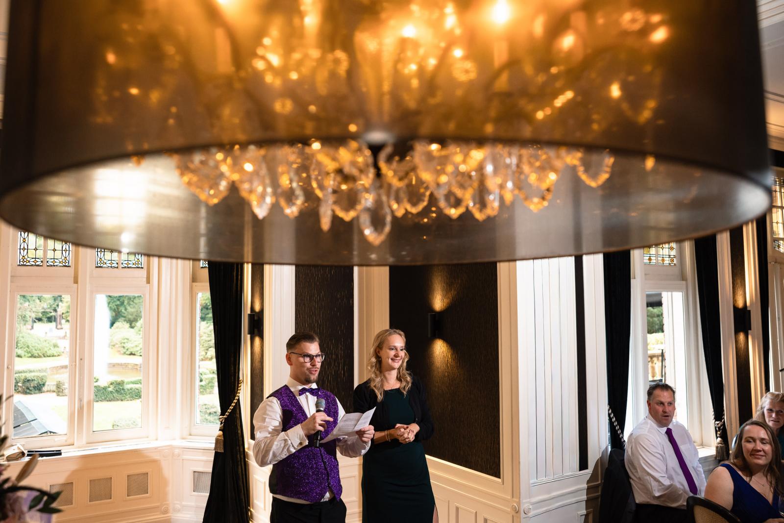 Broer en vriendin van het bruidspaar houden een toespraak tijdens het diner in de sfeervolle trouwzaal.