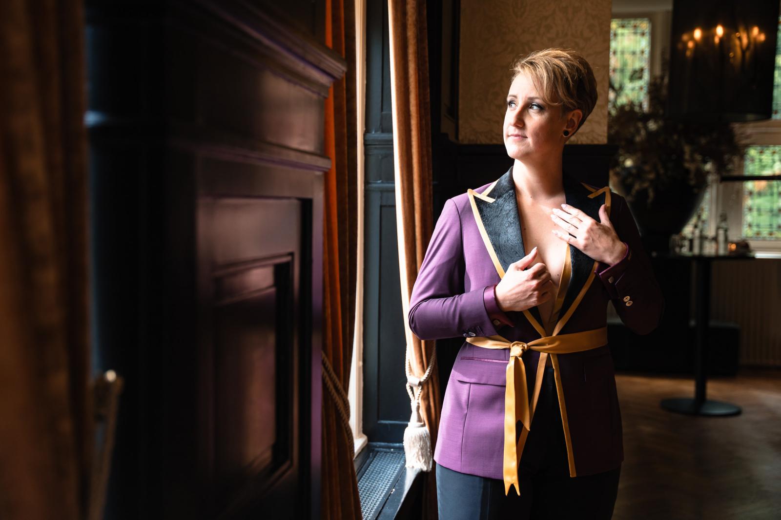 Een van de bruiden kijkt rustig uit het raam terwijl ze zich klaarmaakt voor de firstlook.