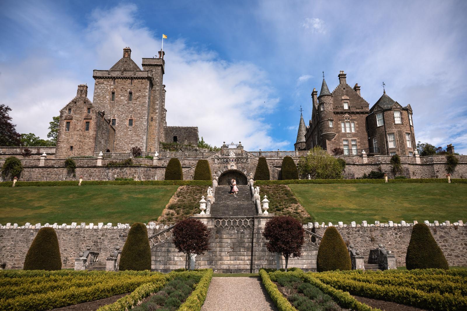 Wide angle shot of Emma and Hamish on the monumental stone staircase of Drummond Castle Gardens during their pre-wedding shoot in Scotland