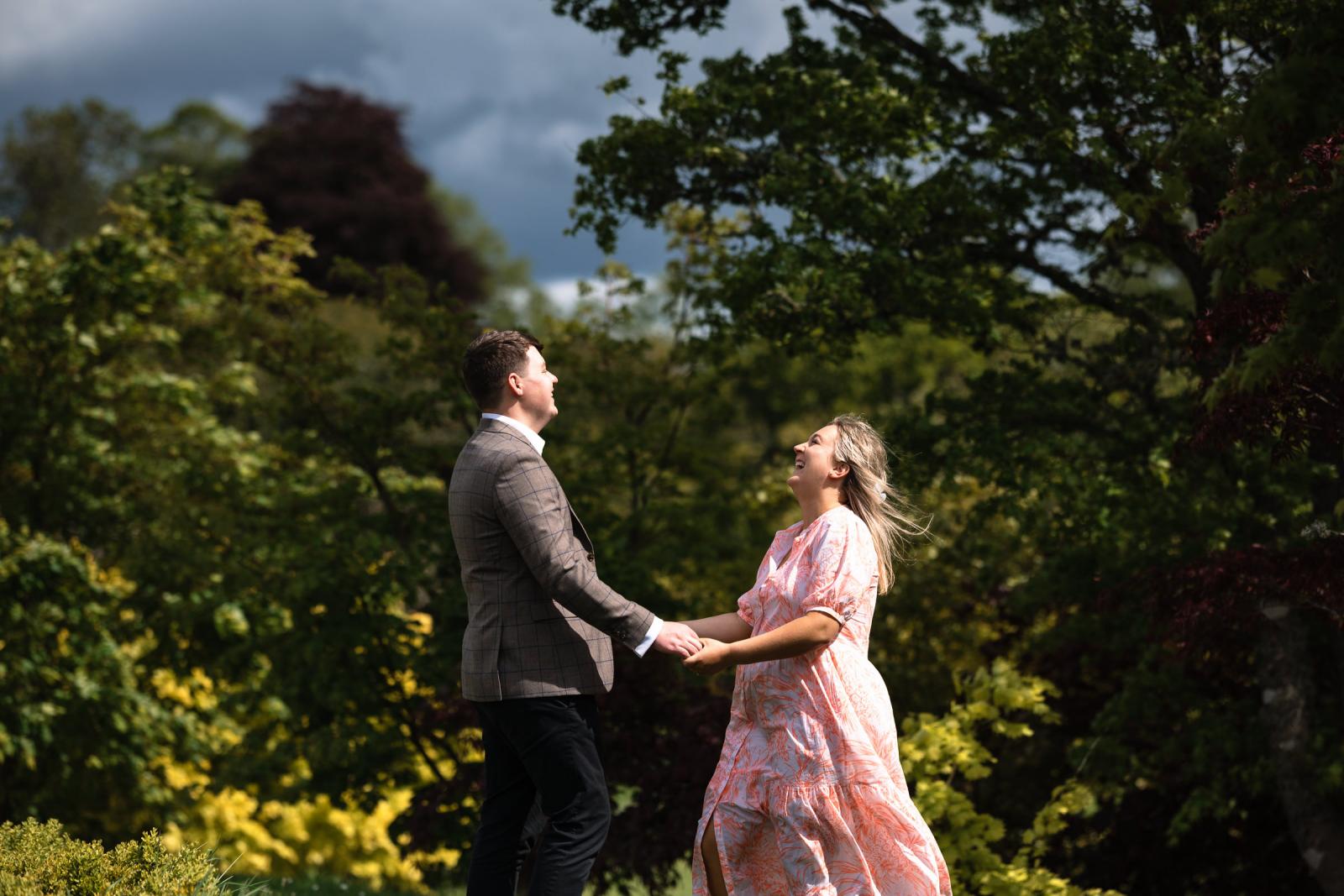Candid and laughing portrait of Emma and Hamish in a lush green setting during their photoshoot in Scotland
