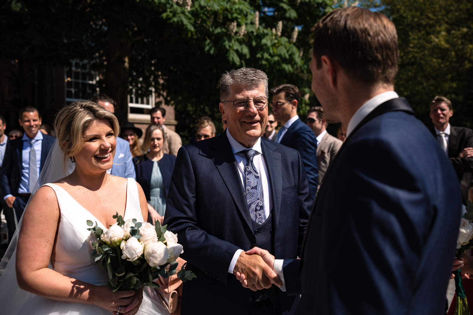 vader geeft bruid weg aan de bruidegom tijdens trouwceremonie Trouwfotograaf Den Haag