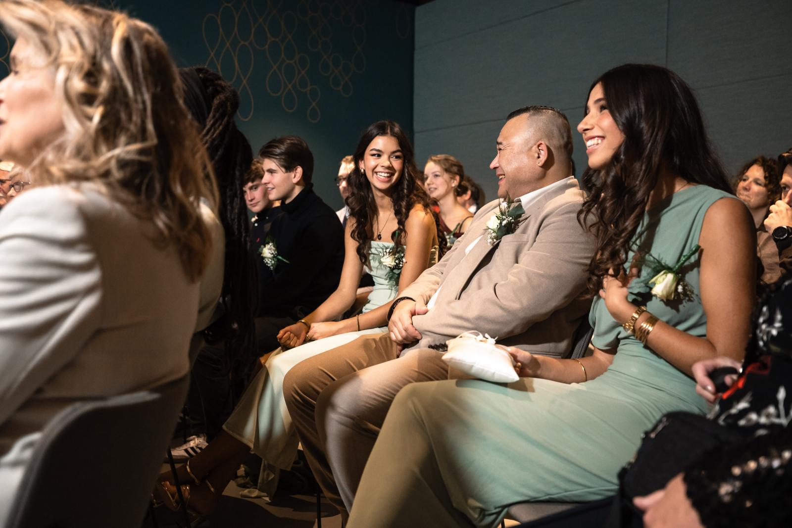 Gasten in de trouwzaal lachen en genieten tijdens de persoonlijke speeches en ceremonie.