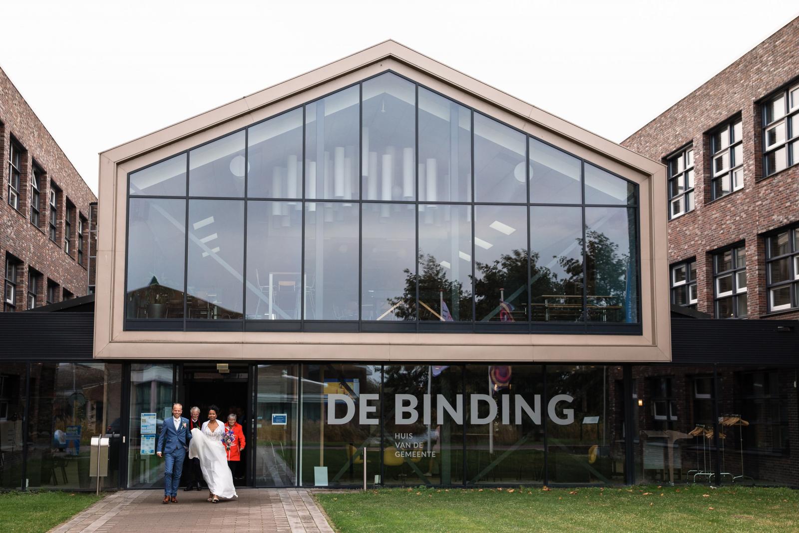 Het bruidspaar loopt stralend de trouwlocatie De Binding uit na de ceremonie.