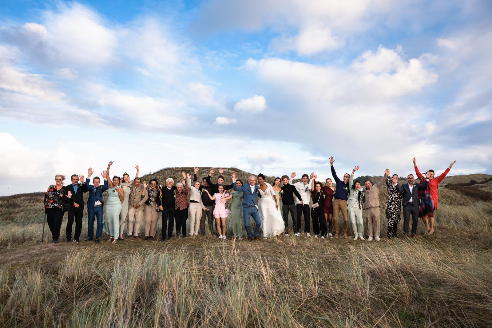 Groepsfoto van Farida, Hans en alle daggasten in de duinen bij Camperduin met blauwe lucht.