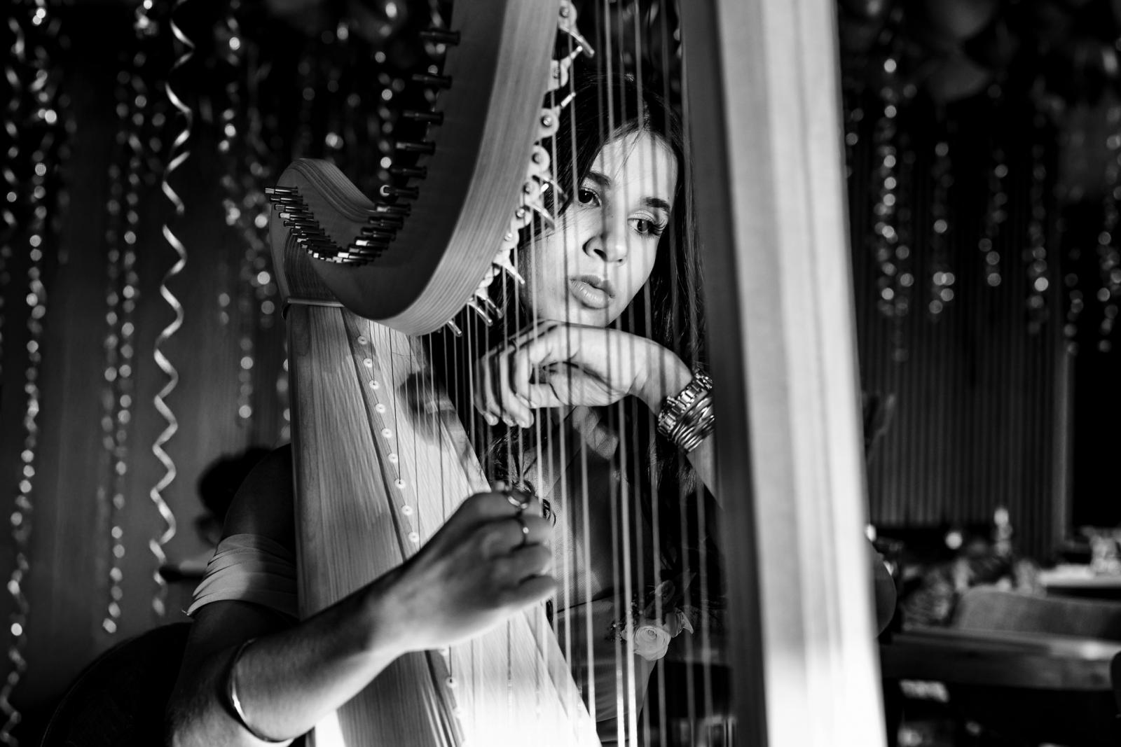 Close-up van dochter die harp speelt tijdens het muzikale optreden op de bruiloft van Farida en Hans.