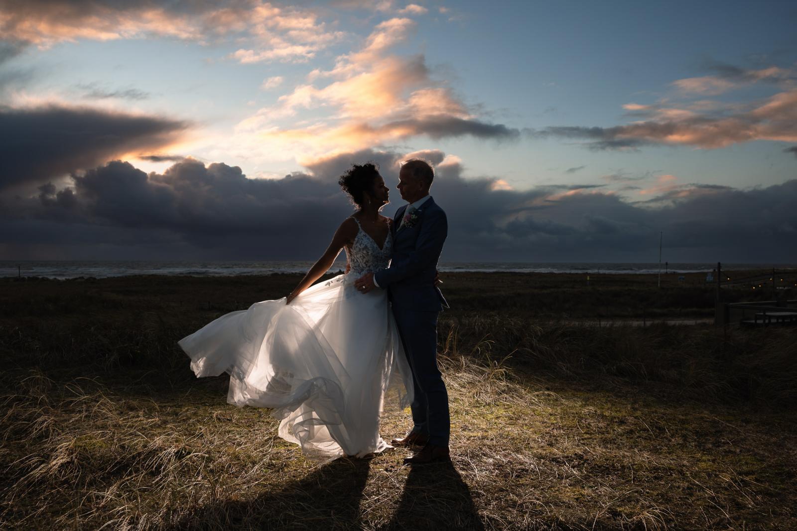 Romantisch silhouet van Farida en Hans bij zonsondergang aan de kust van Camperduin.