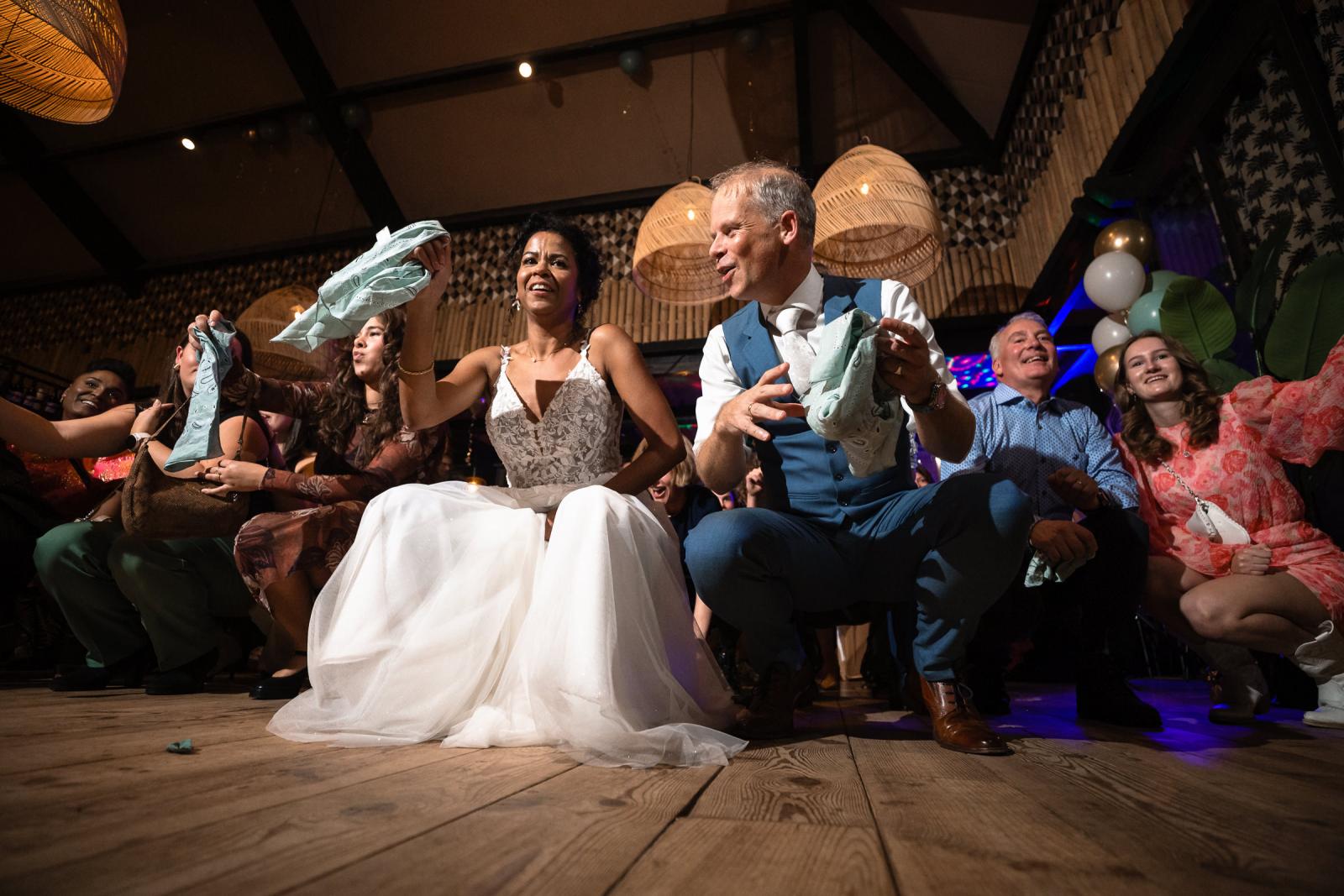 Bruid en vrouwelijke gasten die dansen en doeken boven hun hoofd zwaaien tijdens het avondfeest.