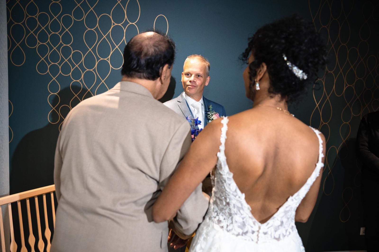 Farida wordt door haar vader naar voren begeleid terwijl Hans liefdevol toekijkt tijdens de ceremonie.