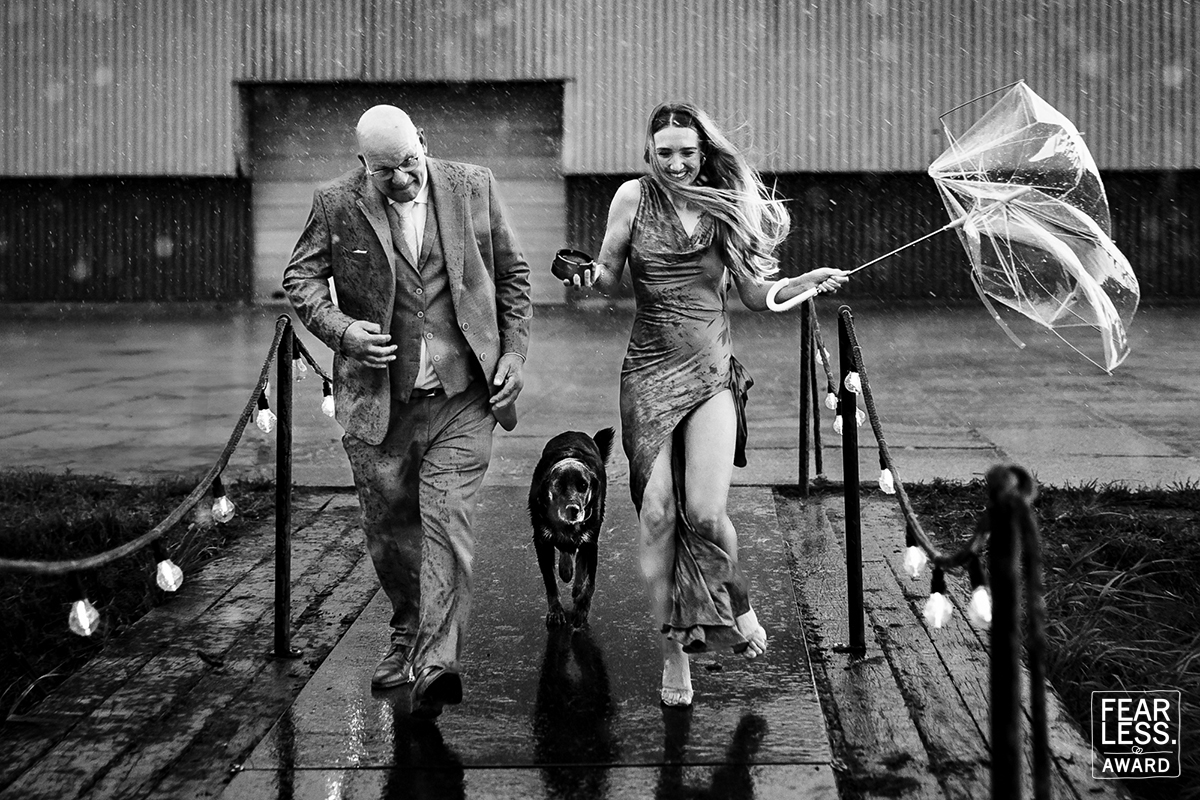 Bruidspaar lacht samen in de regen met hun hond – spontane en echte trouwfotografie