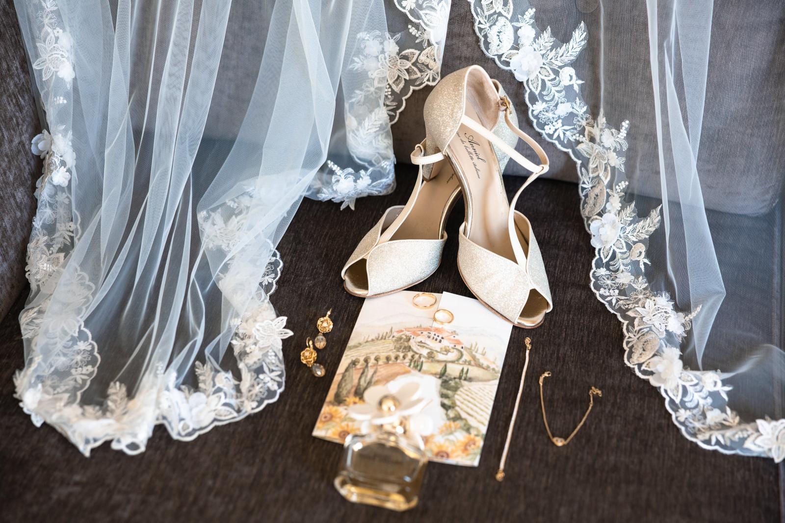 Flat lay detail shot of bridal shoes, wedding rings, lace veil, and custom Italian stationary