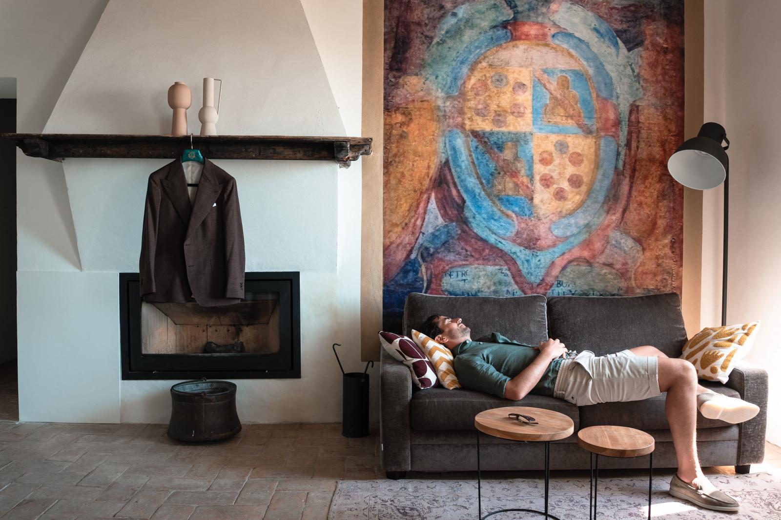 Groom Niels relaxing on a sofa in a rustic villa room before getting ready for his Italian wedding