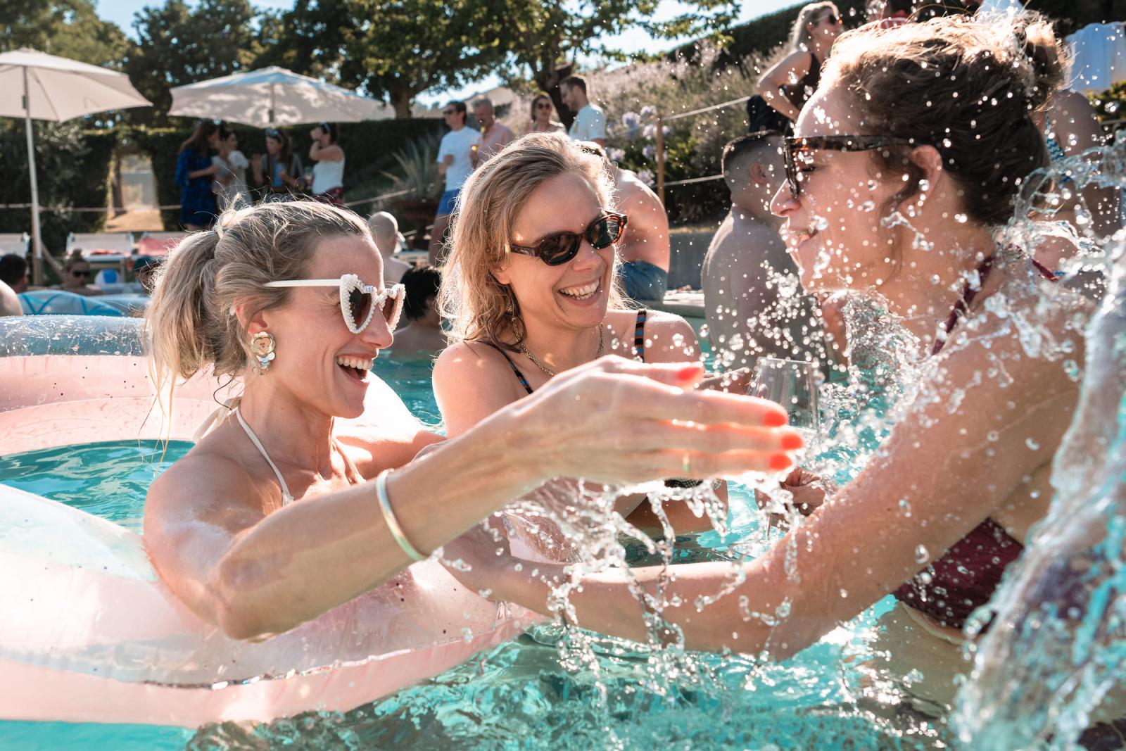 Wedding guests splashing and laughing in the pool during a welcome party in Italy