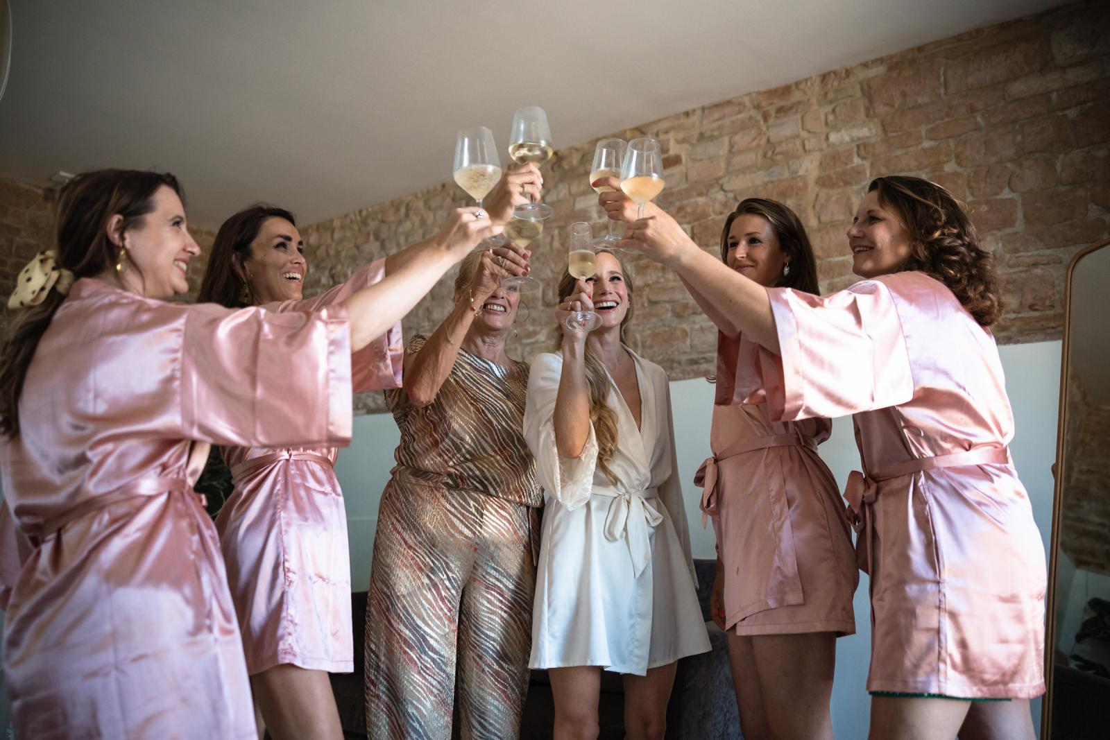 Bride and bridesmaids raising a prosecco toast in matching silk robes during morning prep