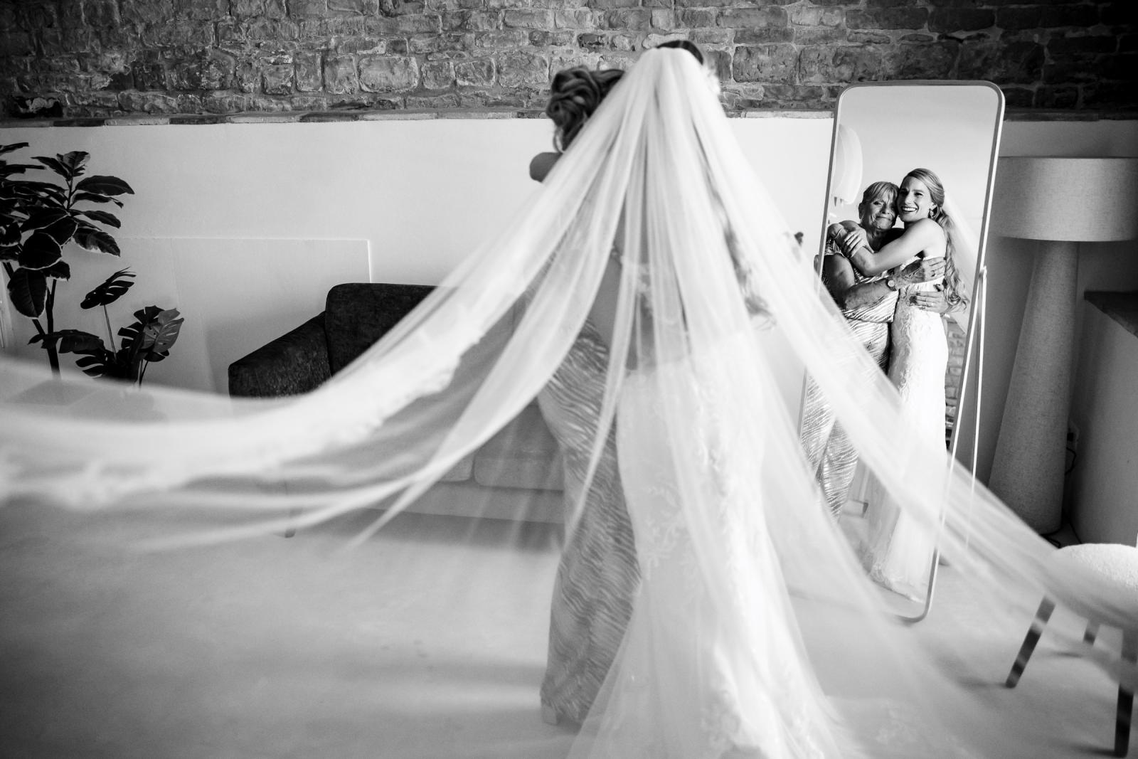 Black and white emotional moment as bride Gemmy hugs her mother in front of a mirror