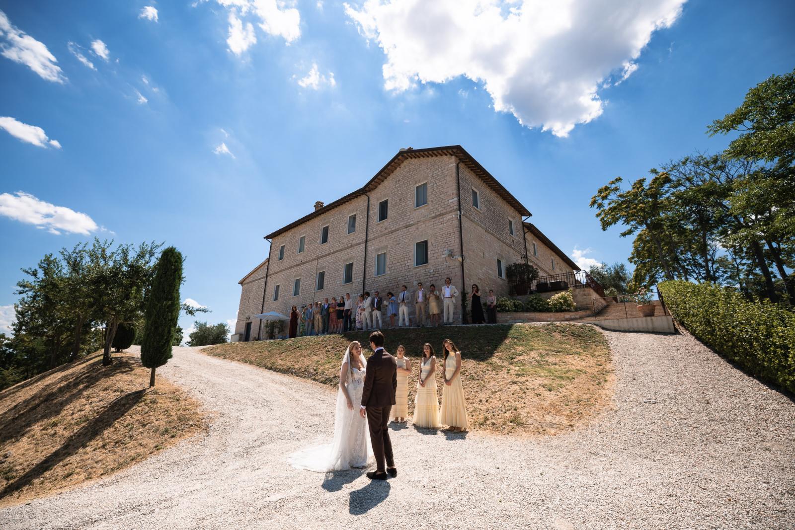 Wide view of emotional first look reveal with wedding guests watching from Le Stonghe terrace