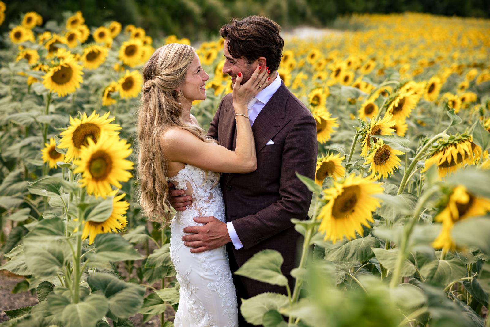 Romantic close-up portrait of bride Gemmy touching groom Niels face surrounded by sunflowers