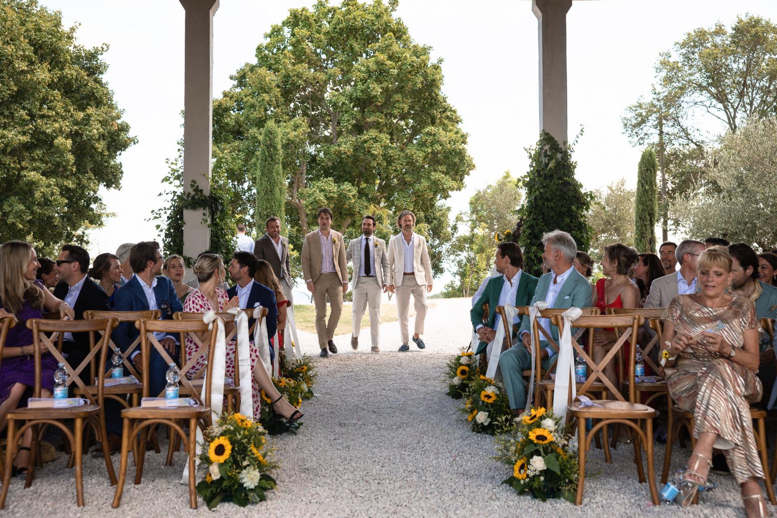 Groomsmen walking down gravel aisle during open-air ceremony at Le Stonghe