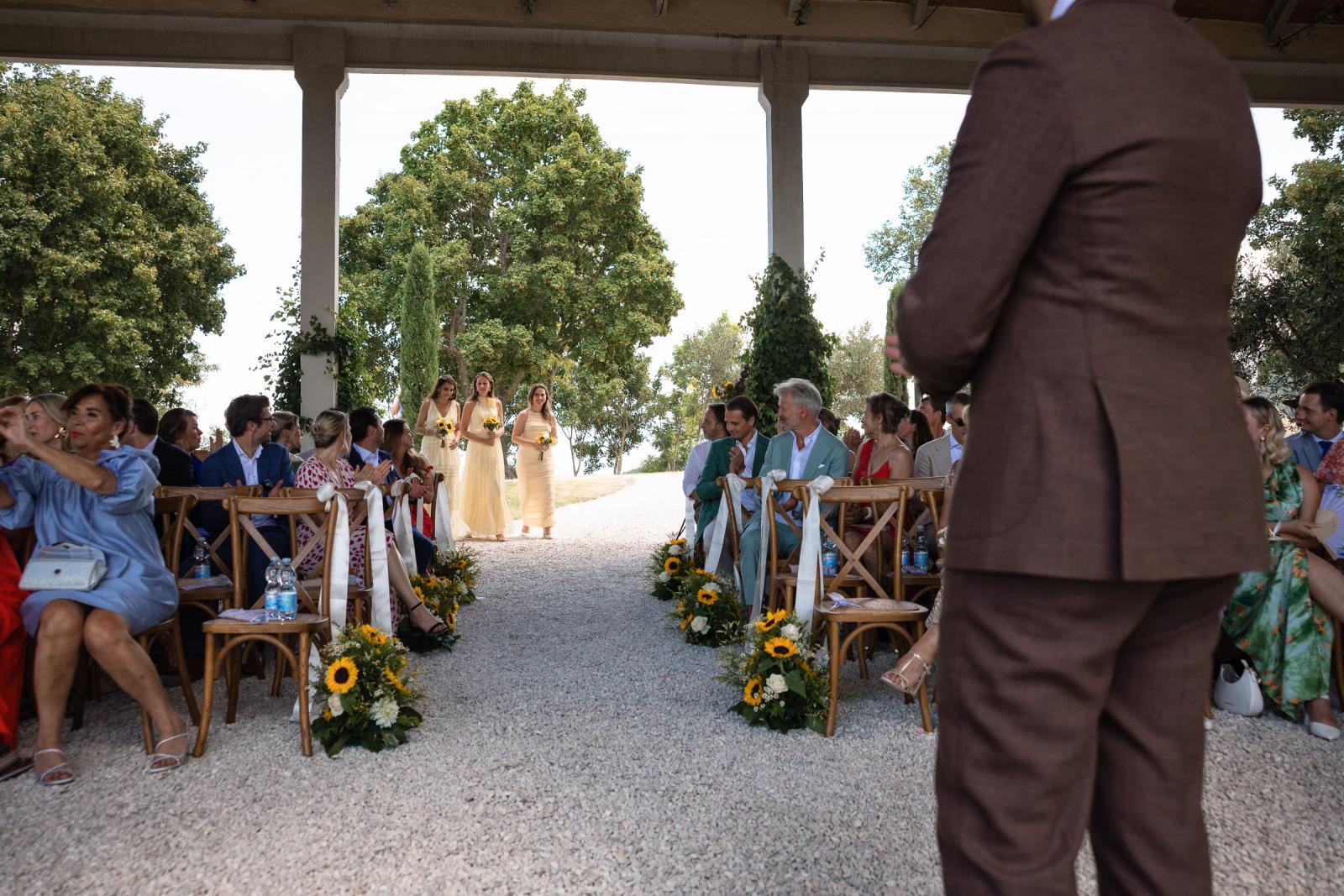 Bridesmaids in soft yellow dresses walking down aisle at Le Stonghe wedding ceremony