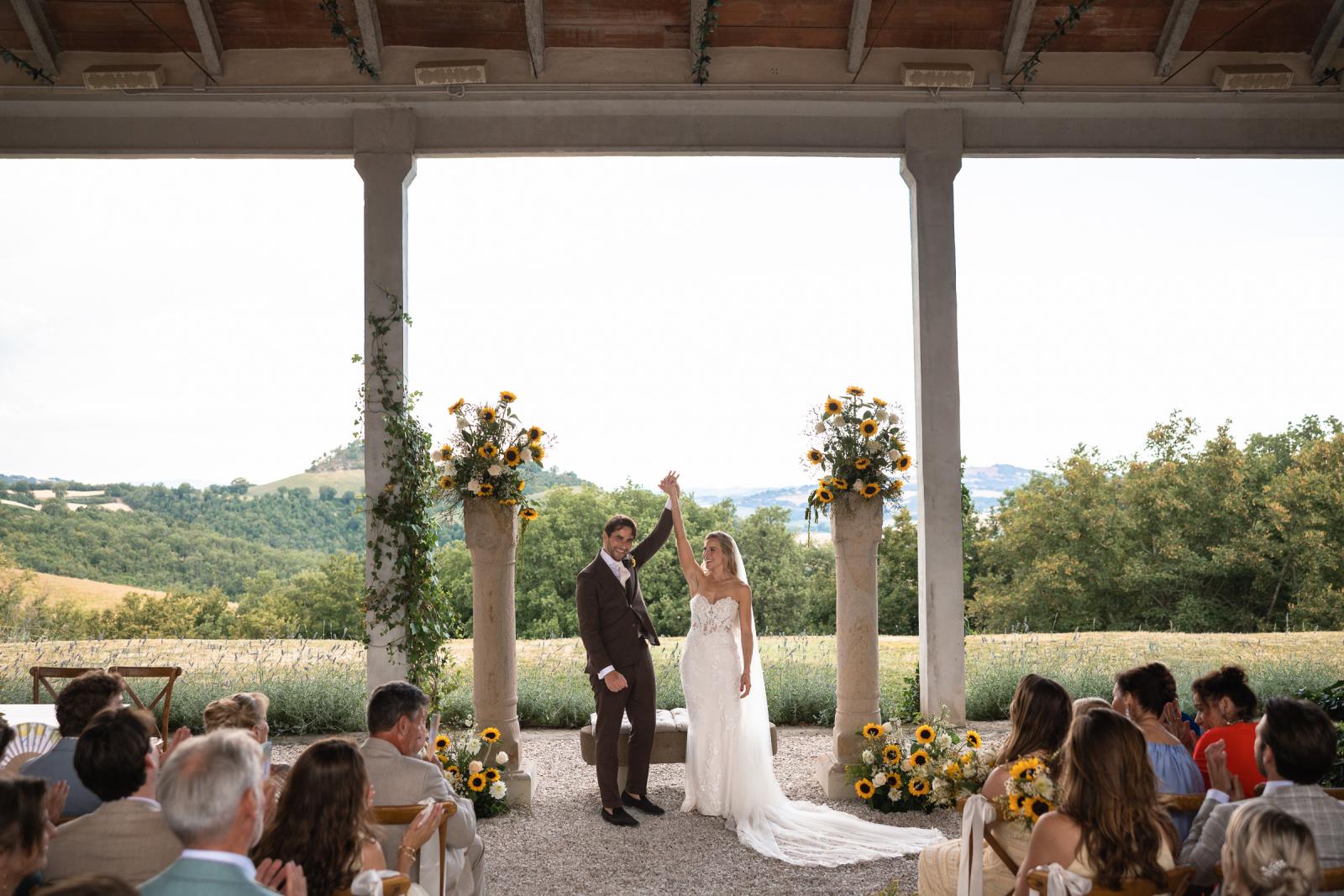 Newlyweds bride Gemmy and groom Niels raising hands in celebration after vows and ring moment